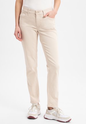 Beige rechte pijpen broek van denim met zijzakken en stikdetails, gecombineerd met witte en beige sportschoenen.
