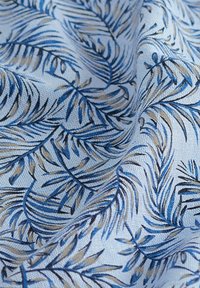Tekstil dengan latar belakang biru muda yang menampilkan pola daun palem yang rumit dalam warna biru tua dan beige, menampilkan kain yang lembut dan bercorak.