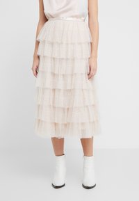 Jupe midi en tulle superposé beige doux avec des pois texturés, dotée d'une fine ceinture et d'une coupe fluide.