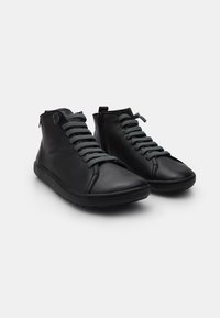 Scarpe alte in pelle nera con lacci grigi, punta rotonda e cerniera laterale per una facile calzata. Superficie texturizzata e elementi di design minimal.