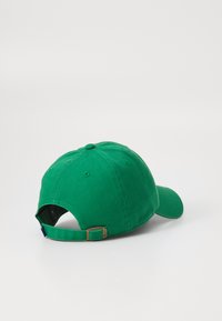 Grønn bomull baseballcaps med buet skjerm, justerbar stropp og sømdetaljer. Glatt tekstur med ensfarget design.