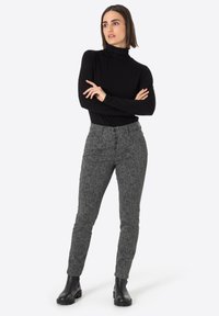 Gray patterned pants with a fitted design, featuring a high waist and button closure. Paired with a black turtleneck and black boots.