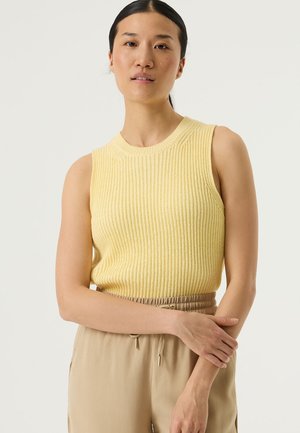 Geel gebreid mouwloos topje met geribbelde textuur, ronde halslijn en aangesloten pasvorm, gecombineerd met beige broek met taillekoord.