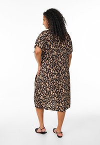 Robe imprimée léopard avec une base noire et des taches de léopard beiges et brunes, manches courtes, coupe décontractée et longueur jusqu'aux genoux.