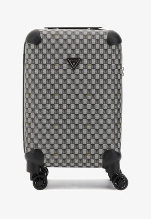 Valise à roulettes avec un motif géométrique noir et blanc agrémenté de touches dorées, coque rigide et quatre roues pivotantes à 360 degrés.