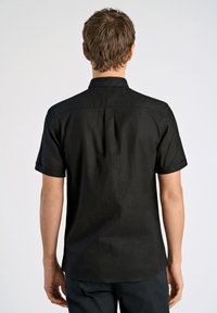 Korte mouw zwarte shirt met een kraagontwerp, gemaakt van een gestructureerde stof. Heeft een rechte achterkant en opgerolde mouwen.