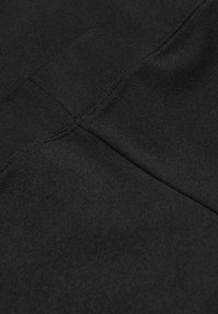 Close-up of black fabric showing intersecting stitched seams and textured knit pattern.