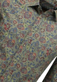 Olijfgroene blouse met bloemenpatroon, featuring rode, blauwe en gele bloemen. Knopsluiting met een klassieke kraag en textuurstof.