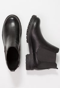 Zwarte chelsea boots met een gestructureerde leren bovenkant, elastische zijpanelen en een robuuste rubberen zool met een visgraatdetail.