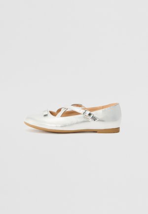 Ballerines métalliques argentées avec un bout rond, des découpes courbes et des lanières croisées. Elles présentent une petite boucle et une semelle en caoutchouc plate.