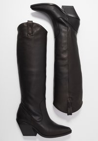 Czarne, skórzane kozaki za kolano z szpiczastym noskiem i obcasem na słupku. Charakteryzują się detalami szwów oraz pętelkami do ściągania u góry.