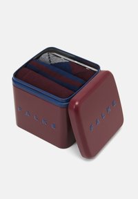 Contenedor de hojalata color burdeos con tapa azul marino, que contiene calcetines enrollados en gris, burdeos y azul con un patrón geométrico. "FALKE" grabado en el lado.