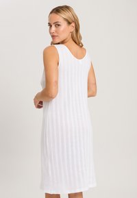 Vestido blanco sin mangas con rayas verticales, con un escote en la espalda y un dobladillo a la altura de la rodilla, fabricado con una tela ligera y transpirable.