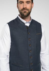 Dunkelblauer Weste aus strukturiertem Stoff, mit Stehkragen, vorderer Knopfverschluss und zwei vorderen Taschen mit kontrastierendem Besatz.