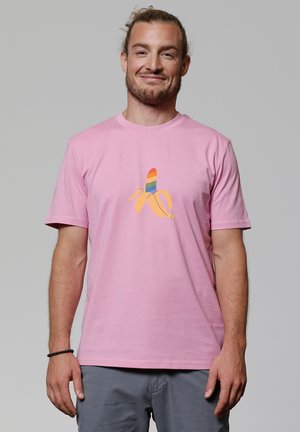 Roze T-shirt met korte mouwen, voorzien van een cartoon-banaanafbeelding met een meerkleurige gestreepte bovenkant. De stof lijkt glad en heeft een ontspannen pasvorm.