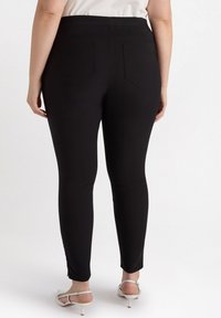 Svarta leggings med slim fit, med bakfickor och hög midja. Slät textur, inga synliga mönster eller metalldelar.
