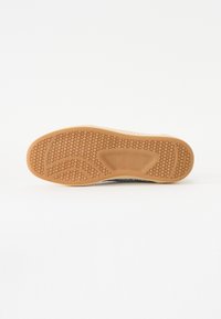 Suola di una scarpa con un motivo a nido d'ape, realizzata in gomma. Il colore è marrone chiaro con una finitura liscia.