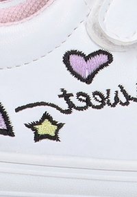 Zapatillas blancas con corazones morados, estrellas amarillas y el texto "sweet" bordado en negro, con un material similar al cuero y una correa de velcro.
