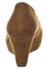 Zapato de tacón cuña de ante marrón con un diseño de talón redondeado, textura suave y suela negra sólida. Presenta un diseño de cuña ancho y ligeramente curvado.