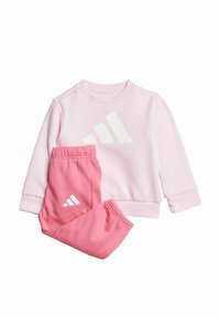 Sweatshirt rose clair avec logo blanc, accompagné de jogging rose assorti portant le même logo. Tissu doux et extensible.