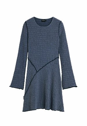 Tmavomodré pletené šaty s dlhými rukávmi, s textúrovaným vzorom a asymetrickým lemom, zdobené kontrastným čiernym prešívaním.