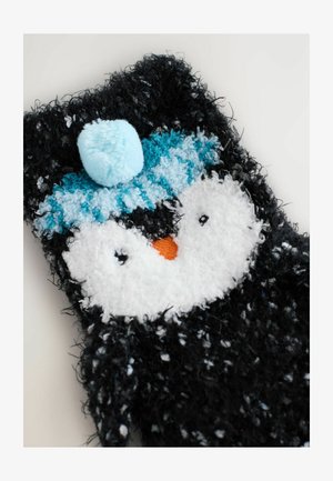 Black and white fuzzy sock featuring a penguin design with a blue striped hat and a pom-pom, accented with an orange beak.
