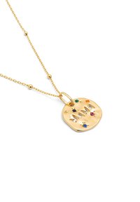 Collar de oro con un colgante redondo texturizado. Inscrito con "MAMA" y adornado con piedras preciosas de colores en acentos verdes, azules y rosas.