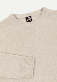 Pull beige en maille à manches longues avec poignets et col côtelés, avec une étiquette noire portant le logo de la marque Colmar au niveau de l'encolure.