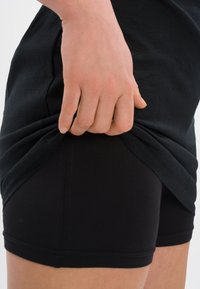 Czarne spodenki sportowe o dopasowanym kroju, wykonane z miękkiego materiału. Posiadają elastyczny pas i gładką, przyjemną w dotyku fakturę.