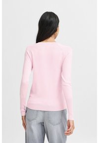 Helles rosa Langarmpullover mit Rundhalsausschnitt, gerippten Bündchen und schmalem Schnitt, aus einem weichen Strickstoff gefertigt. Sichtbare Nähte setzen Akzente.