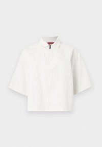 Λευκό κοντομάνικο μπουφάν με φερμουάρ μπροστά και μικρό γιακά, απλωμένο επίπεδα σε απλό φόντο.