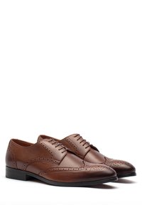 Scarpe stringate in pelle marrone con dettagli brogue, punta rotonda, superficie liscia e tacco basso. Design classico con accenti perforati.