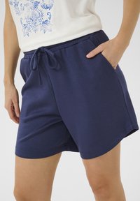 Shorts di cotone blu navy con vita elastica e cordoncino, dotati di tasche laterali e superficie liscia; vestibilità comoda.