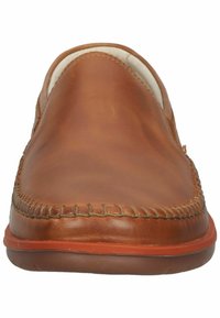 Zapatos de piel marrón sin cordones con detalles cosidos en la puntera y una suela de goma naranja en contraste, presentando una parte superior suave y una forma redondeada.