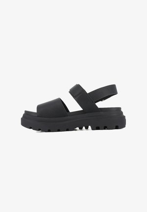 Black sandal featuring a smooth material, wide band across the toe, adjustable ankle strap, and rugged outsole with visible tread pattern.