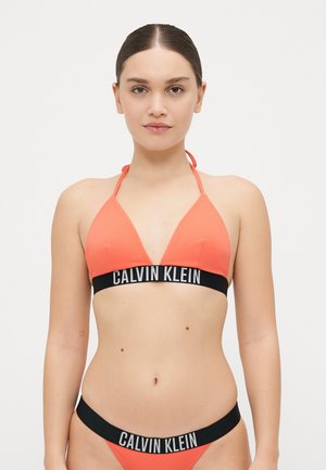 Orange ribbad bikiniöverdel med en svart Calvin Klein-logoband, med triangulär design och halterneckremmar; matchande bikinitrosor ingår.