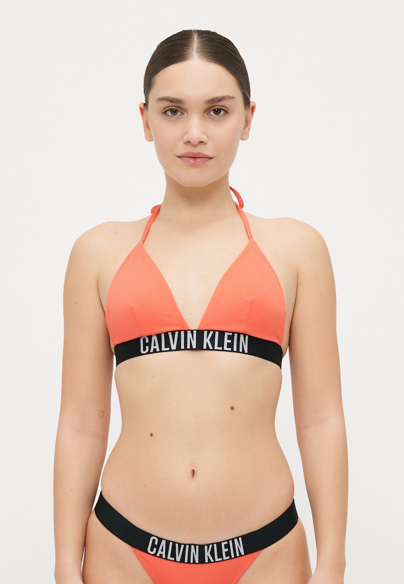 Pomarańczowy stanik bikini z prążkowanej tkaniny z czarną bandą z logo Calvin Klein, z trójkątnym fasonem i ramiączkami na szyi; w komplecie równie�ż dopasowane majtki bikini.