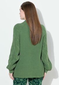 Maglione verde lavorato a maglia con maniche in cable-knit testurizzato e un corpo liscio a contrasto. Il design presenta una vestibilità rilassata e polsini a coste.