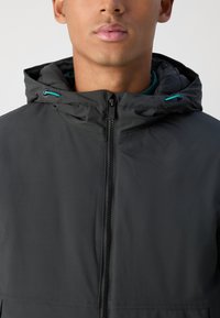 Black hooded jacket featuring a front zipper, teal accents on drawstrings, and a smooth, matte fabric texture. Close-up view.