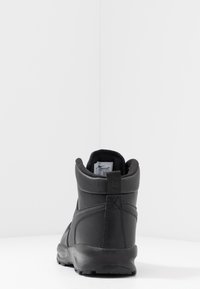 Black ankle boot with a textured synthetic upper, reinforced heel, and a smooth sole. Features a pull tab at the back for easy wear.