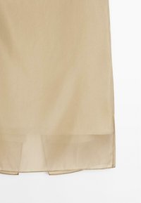 Beige knee-length skirt made of lightweight fabric, featuring a straight cut and subtle sheen, with a smooth texture and a hem finish.
