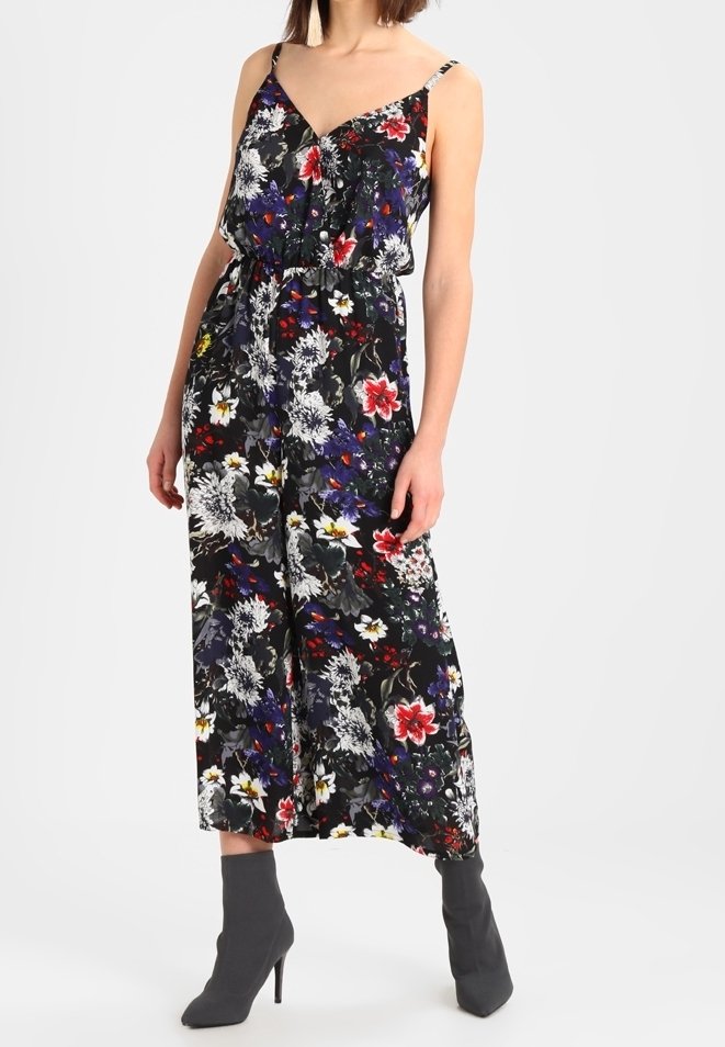 Combinaison florale avec un fond noir et des fleurs multicolores, bretelles spaghetti, coupe décontractée et taille cintrée.