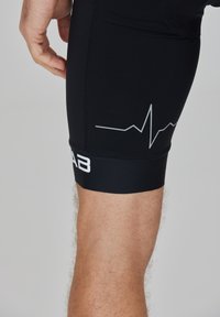 Schwarze Sportshorts mit glatter Textur, ausgestattet mit einem weißen Herzschlaglinien-Design und einem Logo am Bund.