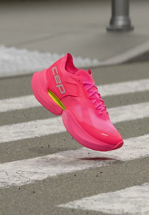 Bright pink running shoe with reflective "cep" logo, mid-air above a road crosswalk with gray pavement background.