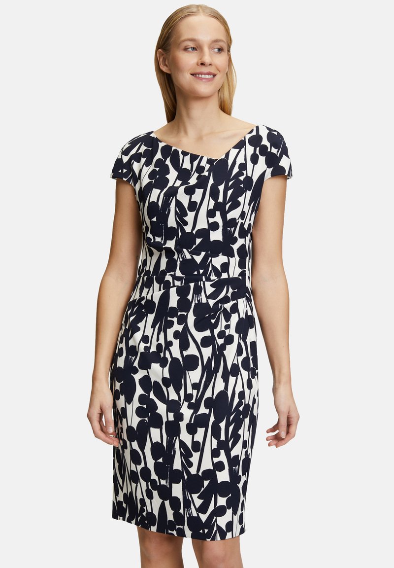 Robe à motif floral bleu marine sur fond crème, avec une coupe ajustée, des manches courtes et un détail de taille froncée.