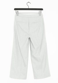 Pantalon large gris clair suspendu à un cintre en plastique noir, avec deux poches arrière et une texture de tissu lisse.