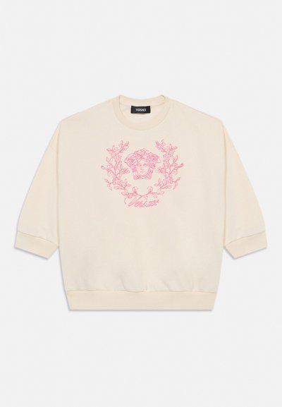 Flødefarvet Versace sweatshirt med lyserødt Medusa-hovedlogo og blomsterværksdesign centreret foran.