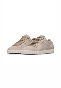 Sneakers in suede beige chiaro con texture liscia, dotati di punte rotonde, chiusura con lacci e suole in gomma bianca rigate.