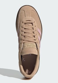 Beige suède sneaker met roze strepen, textuur bovenkant, ronde neus en gevoerde tong. Voorzien van gouden branding op de zijkant en een geprint binnenzool.