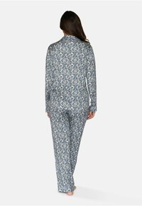 Långärmad pyjamasset i vitt och marinblått med ett intrikat blommönster. Mjuk tyg, avslappnad passform, med knäppskjorta och matchande byxor.